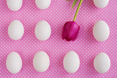 White eggs and pink flower on polka dot fabric, top viewの写真素材