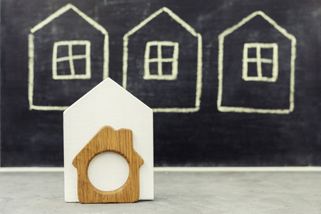 Miniature wooden house on drawn houses background, home conceptの写真素材