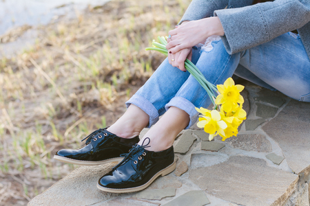 Woman sitting and holding yellow flowers in her hands, spring conceptの写真素材