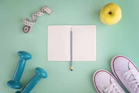 White sneakers, notebook, dumbbells, apple and tape measure on mint backgroundの写真素材