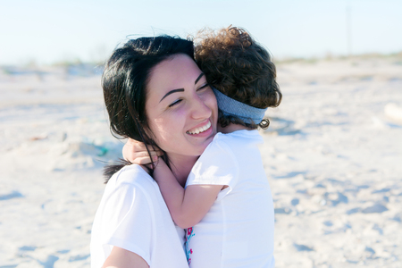 mom and doughter on the beach, hugging togetherの写真素材