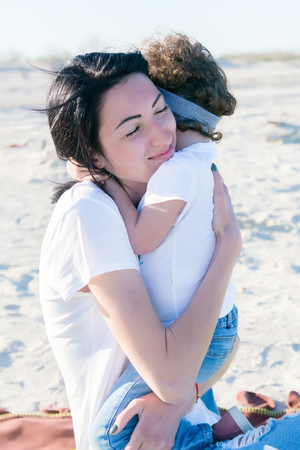 mom and doughter on the beach, hugging togetherの写真素材
