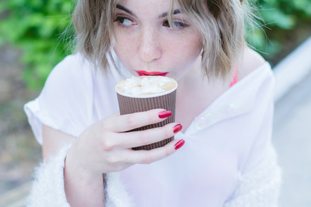 Girl with red lips drinks cappuccinoの写真素材