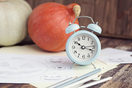 Pumpkings, pencil sketches and alarm clock on brown wooden table, halloween concept.の写真素材