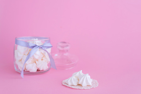 White meringues in glass jar on pink backgroundの写真素材