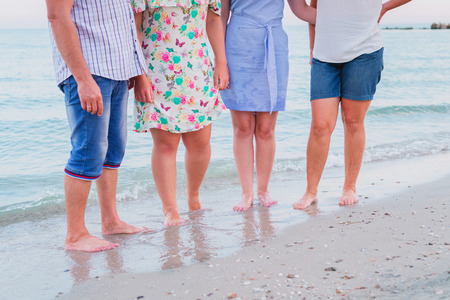 Family of four is standing barefoot on the seashore, cropped.の写真素材