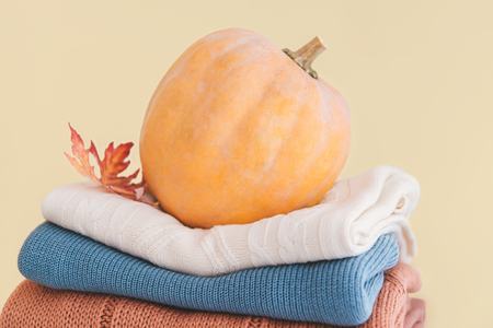 Orange pumpkin on stack of warm folded sweaters. Halloween concept.の写真素材