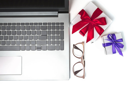 Laptop, gifts with ribbons and glasses on white isolated background.の写真素材