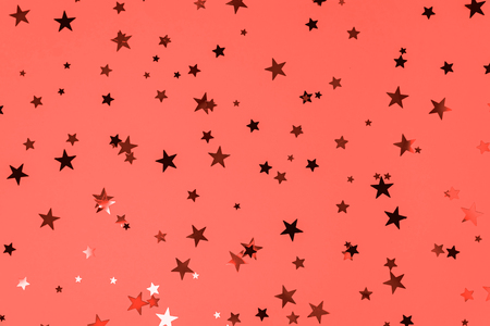 Delicate glitter star confetti on living coral background. Creative and moody color of the picture. Color of the 2019 year.の写真素材