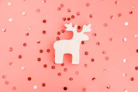 White wooden christmas decotartive deer glittering confetti on coral background. Festive concept.の写真素材