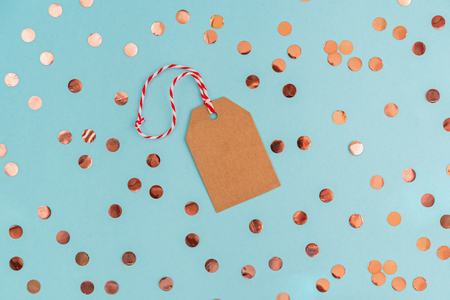 Christmas craft paper tag on blue background with coral confetti. Minimal styled banner with copy space.の写真素材