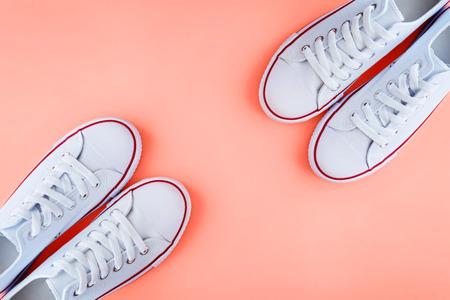 Two pairs of white sneakers on coral background. Color of the 2019 year.の写真素材
