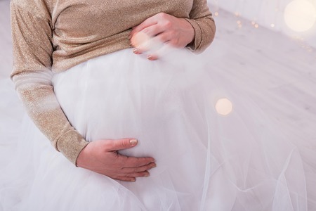 Close up of woman's hands touching pregnant belly. Cropped.の写真素材