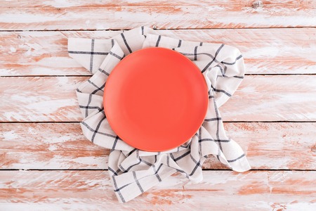 Empty coral circle plate on wooden table with linen napkin. Overhead view. - Imageの写真素材