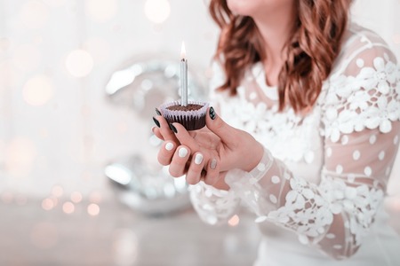 Birthday chocolate cupcake with candle in womans hands.の写真素材