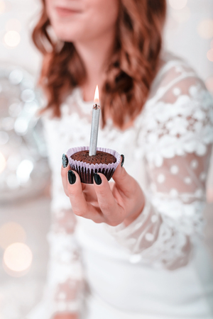 Birthday chocolate cupcake with candle in womans hands.の写真素材