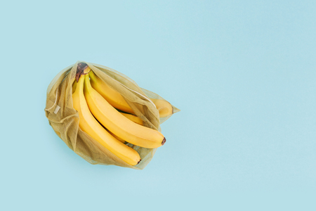 Reusable bag with bananas on blue background. Zero waste and plastic free shopping concept. Copy space.の写真素材