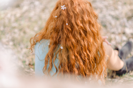 Curly red hair with white blossom, back view.の写真素材