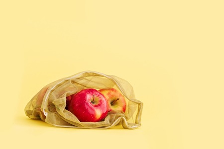 Reusable bag with red apples on yellow background. Zero waste and plastic free shopping concept.の写真素材