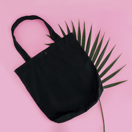 Black cotton bag and palm leaf on pink background. Mock up for design. Square.の写真素材