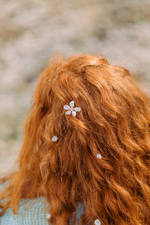 Curly red hair with white blossom, back view. Close up.の写真素材
