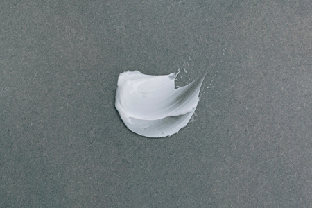 White smear of cosmetic cream on grey background. Cosmetics concept. Top view.の写真素材