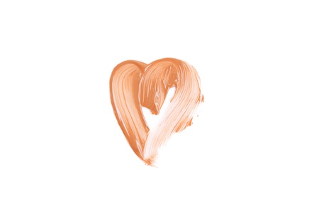 Beige smear of foundation heart shaped. Cosmetics concept isolated on white background. Top view.の写真素材