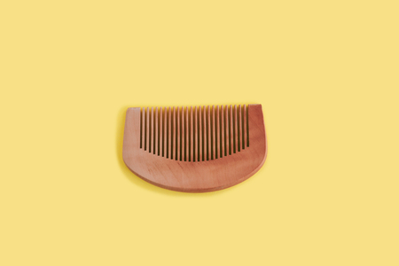 Wooden flat comb hairbrush on yellow background. Zero waste concept. Top view.の写真素材