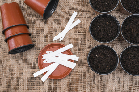 White tags and brown pots with soil on sackcloth background.の写真素材
