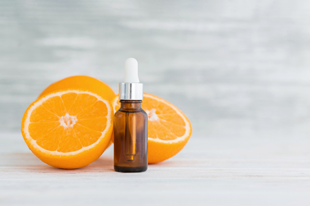 Bottle with citrus natural orange essential oil on wooden background.の写真素材