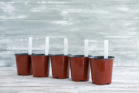 White tags in brown pots on grey wooden background.の写真素材