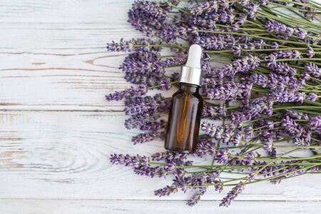 Lavender herbal oil and lavender flowers on grey wooden background. Top view. Copy sapce.の写真素材