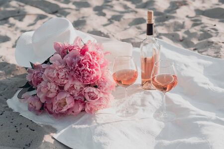 Two glasses of rose wine and peony bouquet on the sunset picnic. Copy space.の写真素材