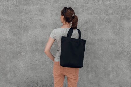 Young woman with black cotton bag in her hands on grey background. Cropped.の写真素材