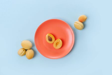 Orange plate with ripe apricots on it on blue background. Top view.の写真素材