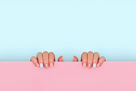 Hands with manicure holding blue and pink background. Copy space.の写真素材
