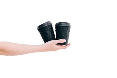 Two black coffee cups to go in woman's hand isolated on white. Unusual shape of cup, mock up. Copy space.の写真素材