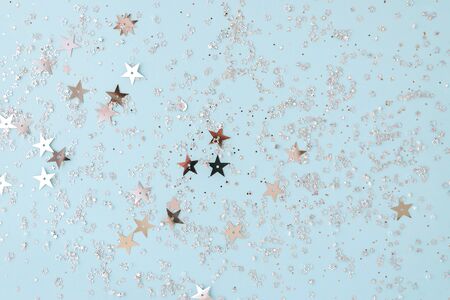 Delicate glitter star confetti on light blue background. Creative and moody color of the picture.の写真素材
