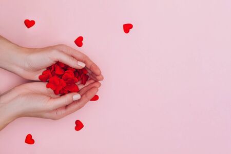 Womans hands full of small red hearts on pink background. Love, care, affection, the St. Valentines day concept.の写真素材