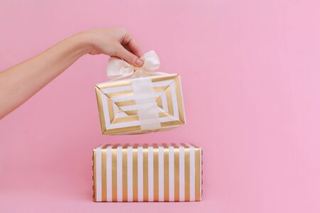 Womans hands holding gift or present box on pink pastel background.の写真素材