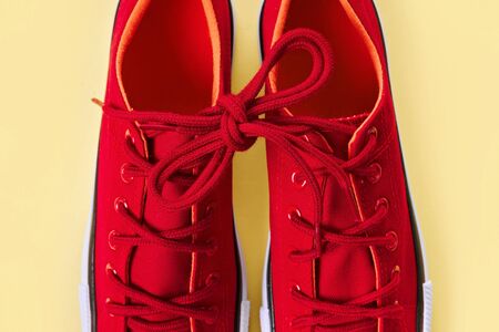 New red sneakers on yellow background with copy space.の写真素材