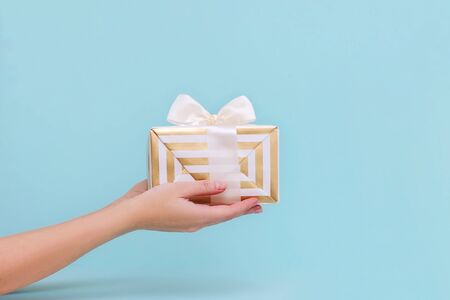 Womans hands holding gift or present box on blue pastel background. Composition for birthday or New year.の写真素材