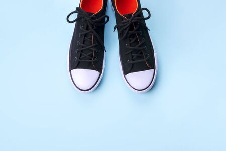 New black sneakers on pale blue background with copy space. Top view.の写真素材