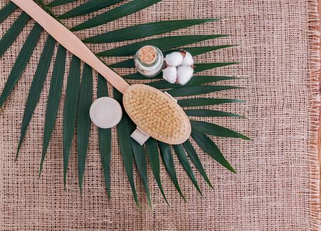 Soap, sea salt in glass bottle, natural brush and cotton flower on palm leaf background.の写真素材