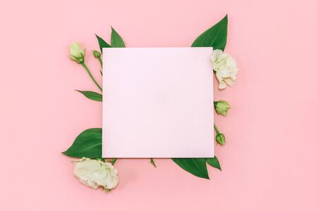 Paper blank with fresh white flowers on pastel pink background. Flat lay, top view.の写真素材
