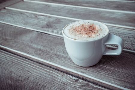 White cup of cappuccino on the grey wooden table with copy space. Close up.の写真素材
