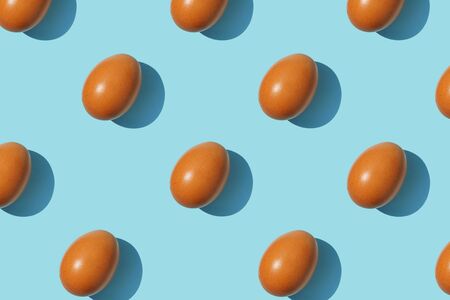 Brown eggs pattern on blue background. Creative layout. Top view.の写真素材