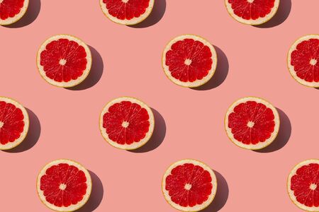 Grapefruit slices pattern on coral background. Minimal flat lay concept. Top view.の写真素材