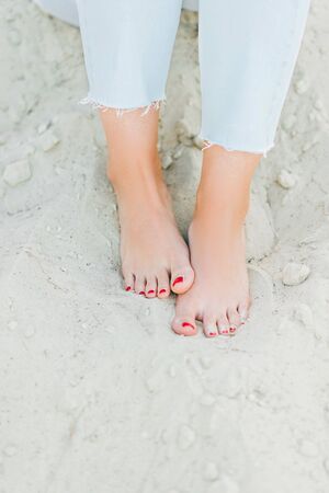 Woman feet with red pedicure in the beach sand. Cropped.の写真素材