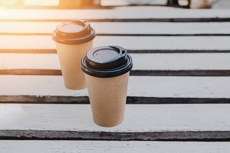 Two paper coffee cups to go on white wooden plank background with copy space.の写真素材